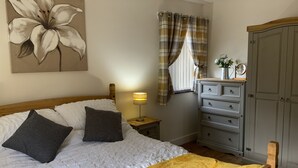 A bedroom with a bed, a bedside lamp, a dresser, and a wardrobe. - St. Mark's Court Holiday Homes - No1 (Marske-by-the-Sea)