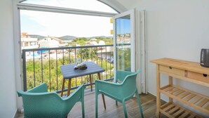 A balcony with a table and chairs, a wooden shelf, and a view of the surrounding area. - Apartment Anna by Interhome (Murter/Jezera)