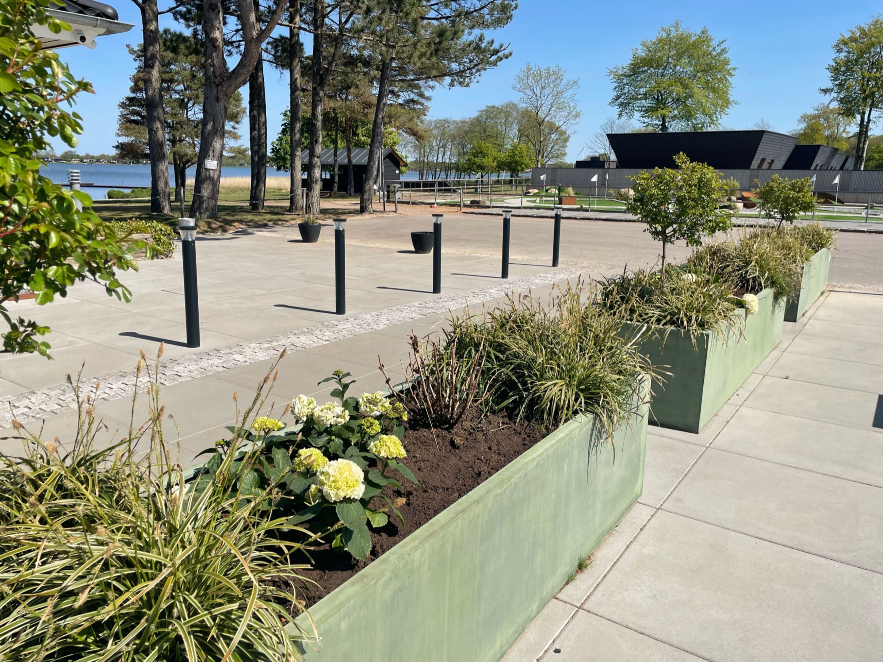 A landscaped area with planters, a pathway, and a building in the background.