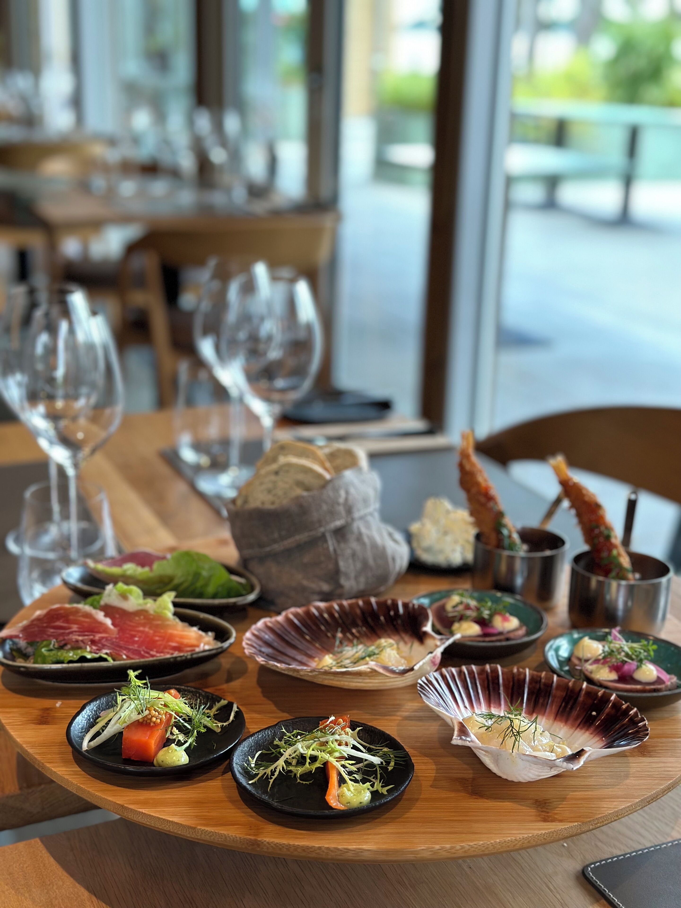 A dining table with various dishes, glasses, and a bread basket.