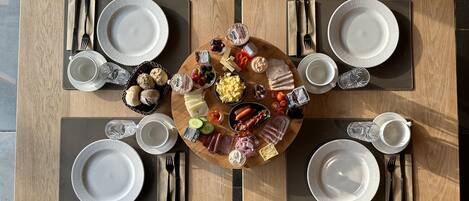A dining table set for four with a variety of foods and drinks, surrounded by wooden chairs.