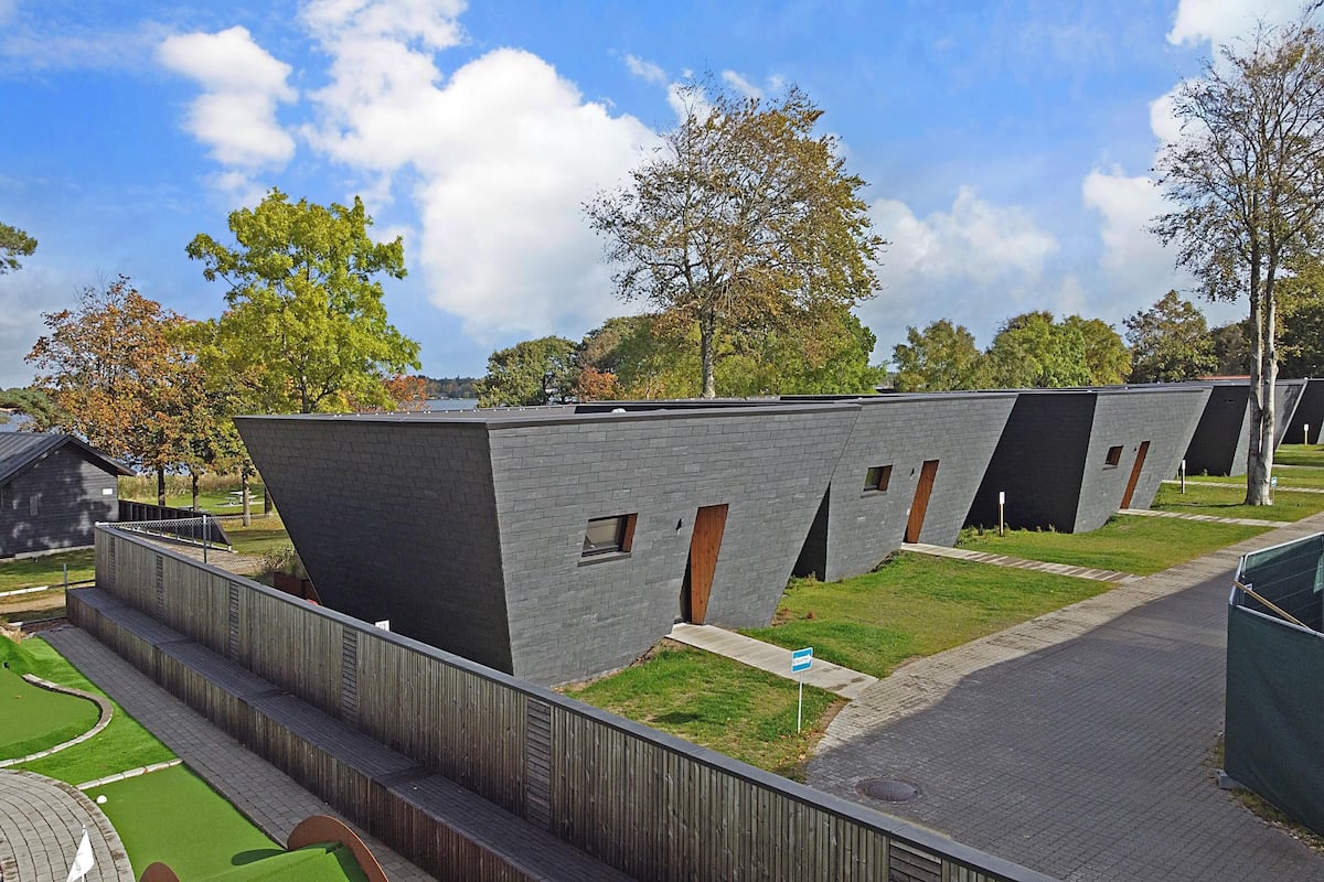 A modern building with a unique angular design, featuring multiple rooms with visible windows and doors.