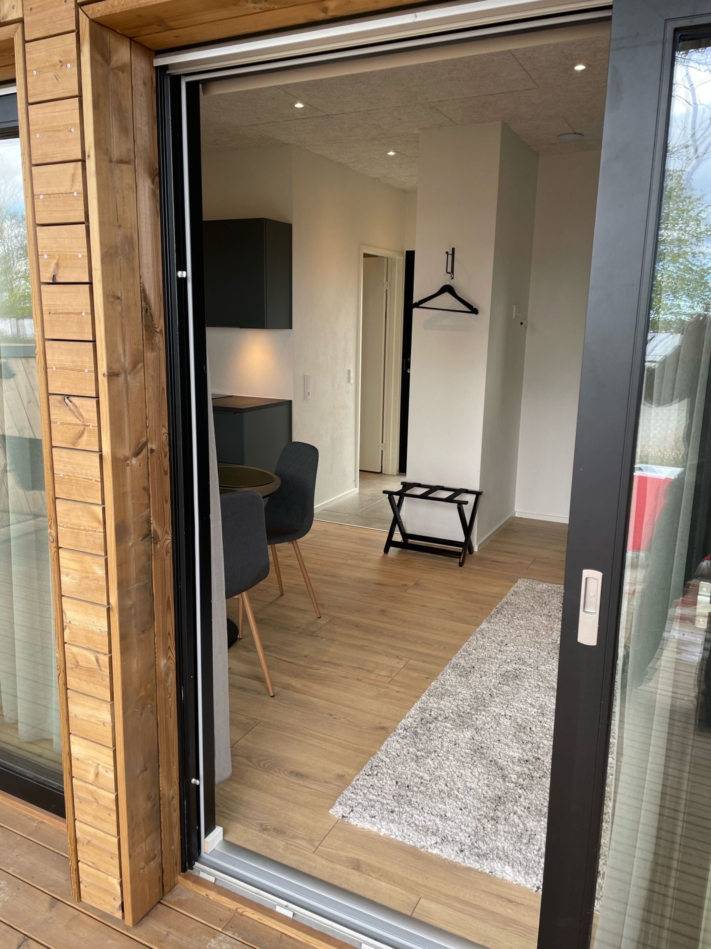 A modern interior with a wooden floor, a grey sofa, a small table, and a hanging coat rack.