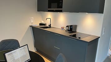 A modern kitchen with a built-in microwave, a coffee maker, and a sink. There is a framed welcome sign on the table.