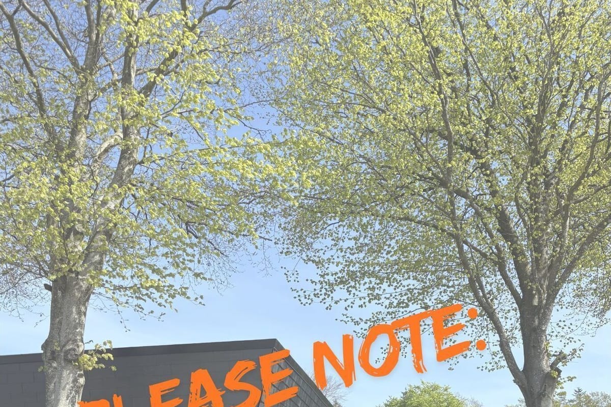 A building with a large black structure and a sign that reads "PLEASE NOTE. NO KITCHEN IN THIS ROOM."