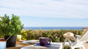 A table set outdoors with a view of the ocean, a potted plant, and a purple cup. - Les Bastides (I3 049) by Interhome (Agay Village Cap Esterel)