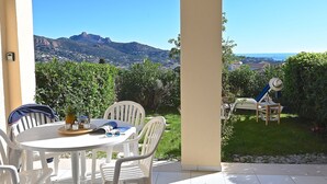 A patio with a table and chairs, a magazine, and a pineapple. - Les Bastides (O5 018) by Interhome (Agay Village Cap Esterel)