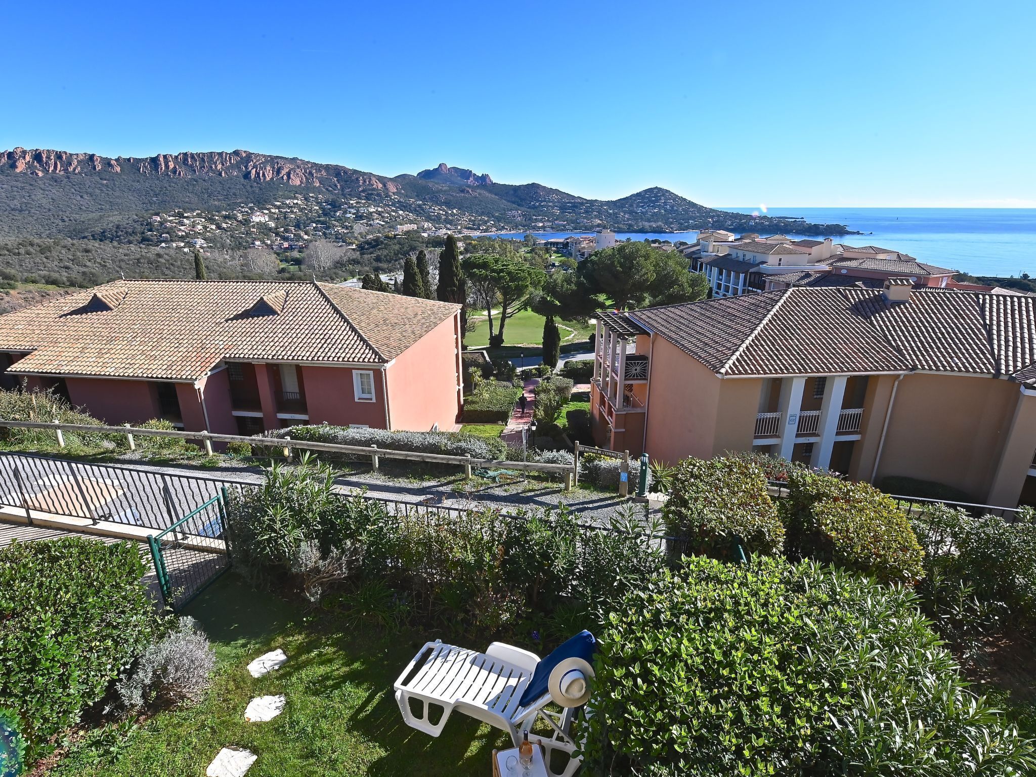 A residential area with houses, a pool, and a view of the sea.