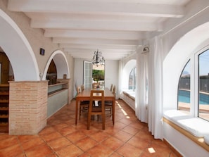 A spacious dining area with a brick column, wooden table, and chairs.