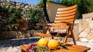 A wooden table with two lemons, a bunch of purple flowers, and two wine glasses filled with red wine. A wooden chair is placed behind the table. - Villa Mandana by Interhome (Dénia)
