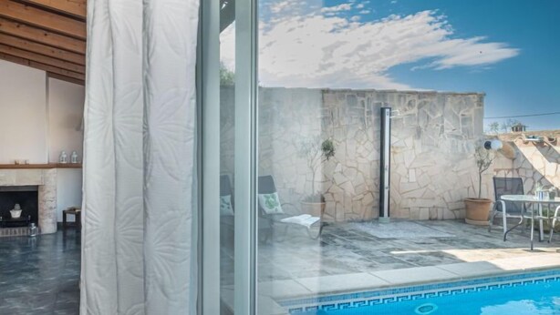 Uma área de piscina moderna ao ar livre, com paredes de pedra e um céu azul claro.