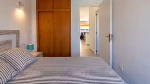 Een slaapkamer met een bed, een houten garderobe en een nachtkastje.