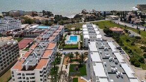 Een kustwoonwijk met een groot zwembad, meerdere appartementencomplexen en uitzicht op zee.