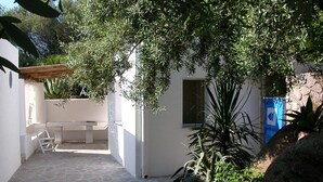 A courtyard with a stone floor, a white bench, and a table. - Cottage with large garden in the center of Panarea (Panarea)