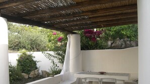 A small outdoor seating area with a table and two chairs, surrounded by white walls and a stone floor. - Cottage with large garden in the center of Panarea (Panarea)
