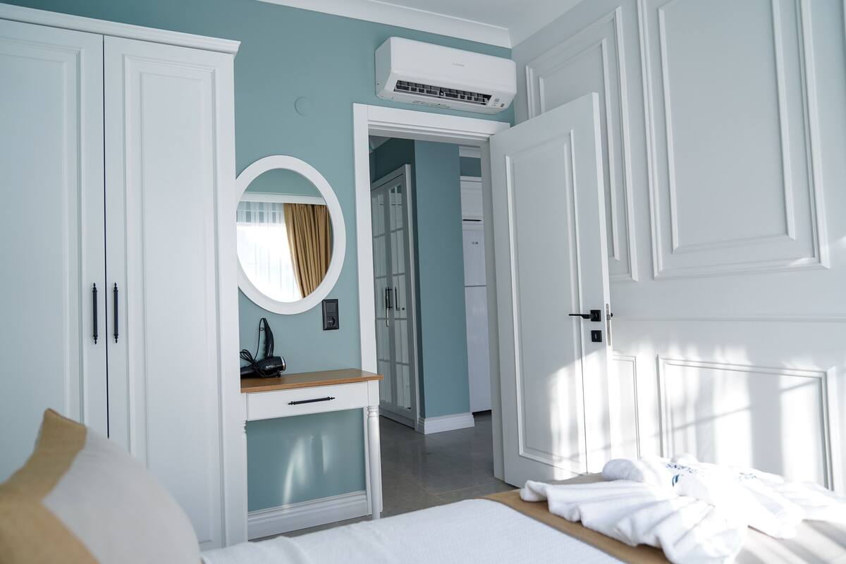 A bedroom with a bed, a bedside table, a mirror, and a wardrobe.