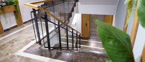 Una escalera moderna con barandillas de vidrio y pasamanos de madera, que conduce a un segundo piso.