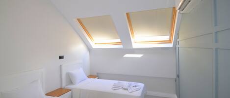 A hotel room with two beds, skylights, an air conditioning unit, and a small wooden nightstand.