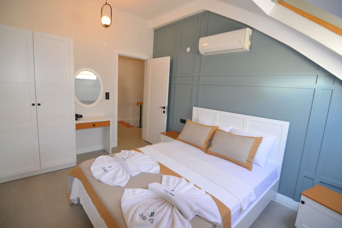 A bedroom with a bed, a wardrobe, a mirror, and an air conditioning unit.