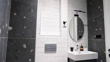 Un baño moderno con un lavabo blanco, un espejo y un toallero.