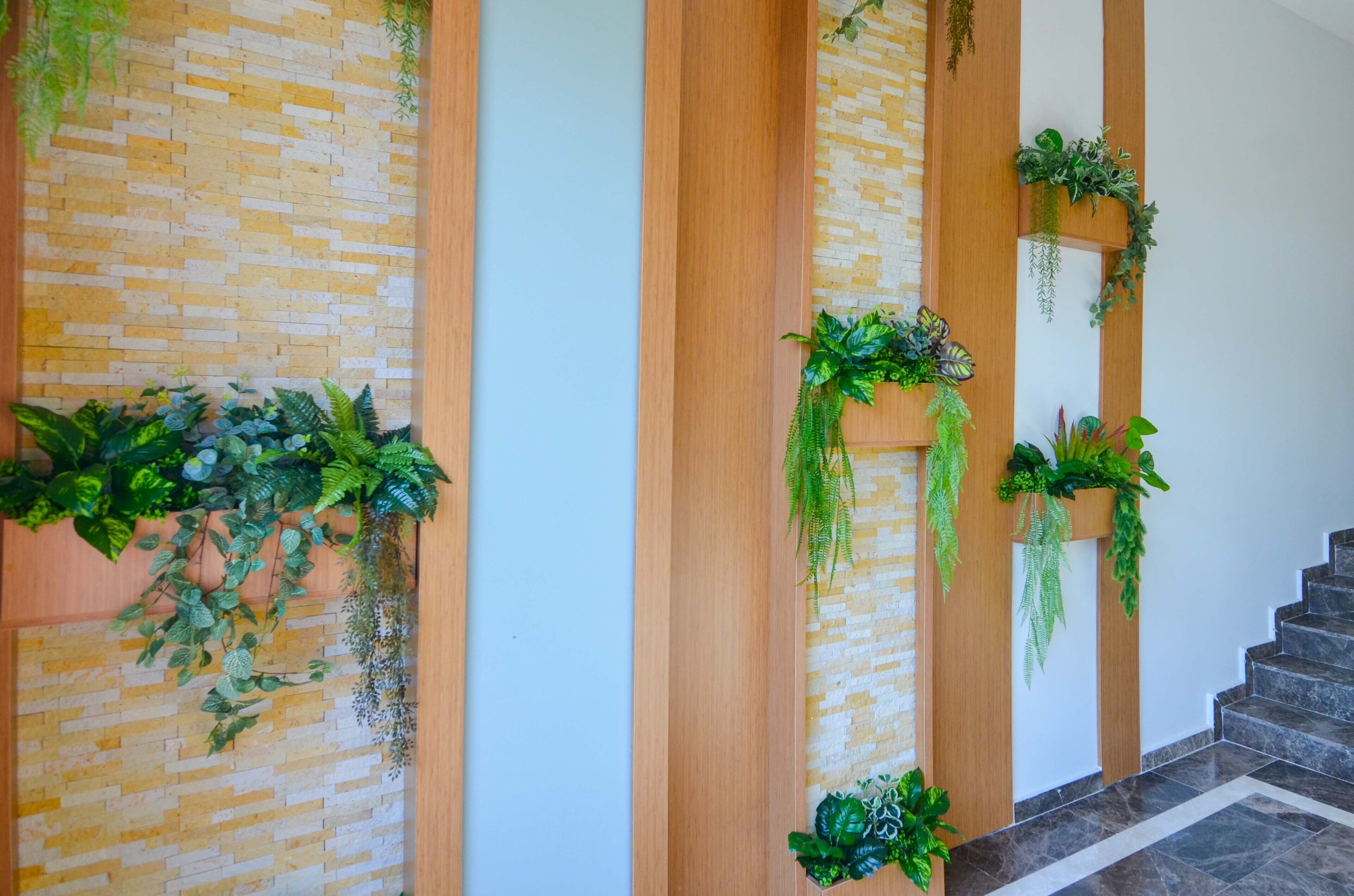 A staircase with a brick wall and wooden panels, decorated with hanging plants.