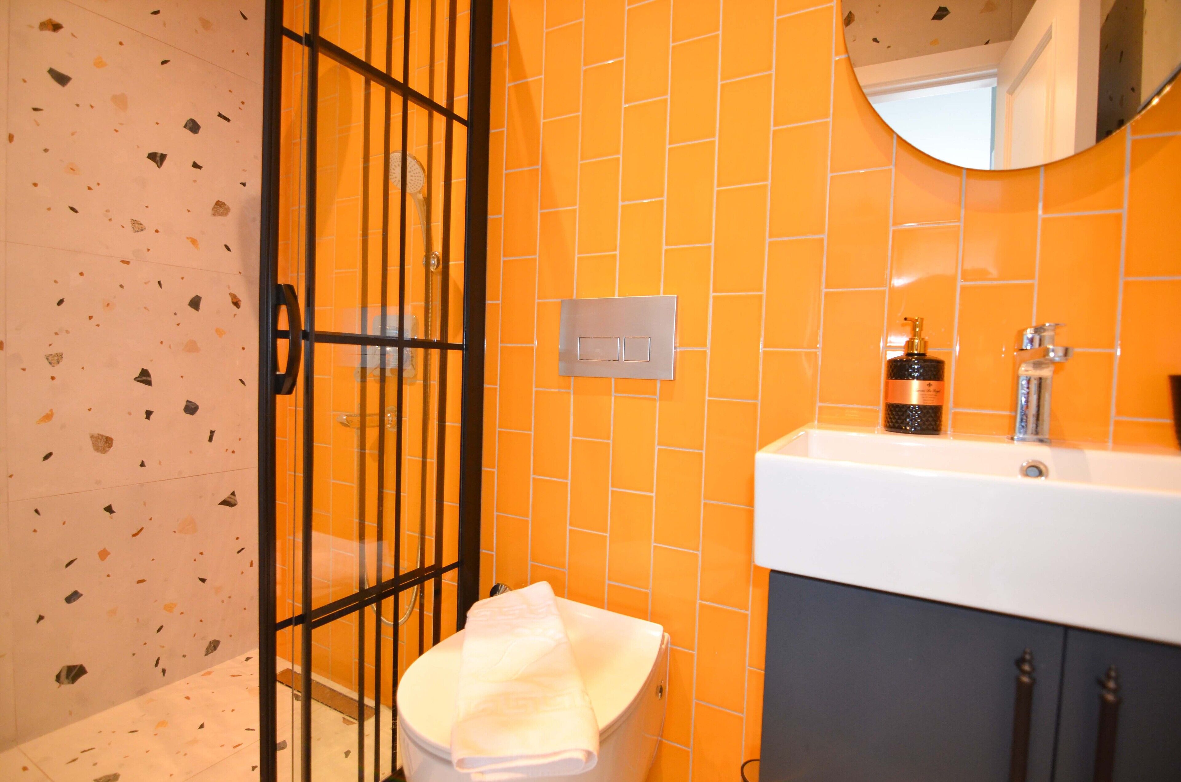 A bathroom with a white toilet, a sink with a soap dispenser, and a mirror above the sink.