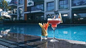 A poolside bar with two cocktails and a glass of fruit.