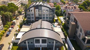 Un hôtel moderne doté d’un toit incurvé, de plusieurs étages et d’un espace piscine.