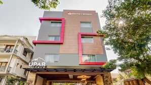Un hôtel au design moderne, avec une enseigne bien visible portant les noms « IDHYA CROWN » et « UPAR HOTELS ».