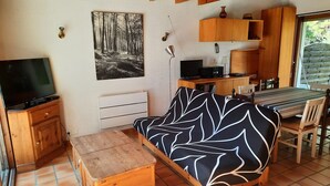 A cozy living area with a sofa, wooden furniture, a TV, and a painting of a forest. - Family Villa with Terrace, Near Beach and Shops in Seignosse (Seignosse)