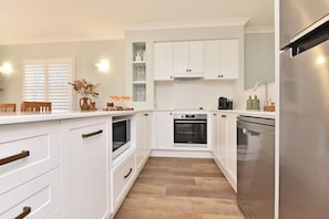 Een moderne keuken met witte kasten, een ingebouwde oven, een magnetron en een roestvrijstalen koelkast.