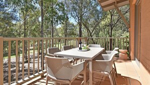 Un patio al aire libre con una mesa, sillas, una botella de vino y una copa.
