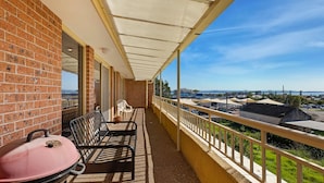 Un balcon avec un barbecue, des chaises et une vue sur la ville.
