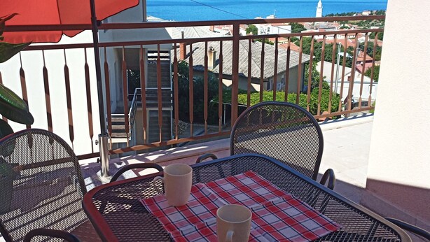 A balcony with a table, chairs, and a red umbrella. - Sea view apartment, 7 minuts from beach (Novi Vinodolski)
