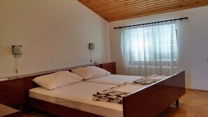 A bedroom with a wooden ceiling, a bed with white bedding, a nightstand, and a window with sheer curtains. - Sea view apartment, 7 minuts from beach (Novi Vinodolski)