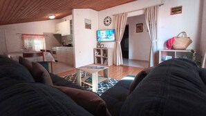 A cozy living room with a sofa, a small coffee table, and a television. There is a kitchen area visible in the background. - Sea view apartment, 7 minuts from beach (Novi Vinodolski)