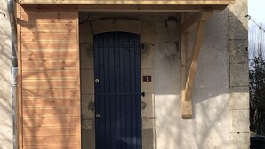 Un edificio con puerta de madera, un letrero con el número 1 y techo de tejas.