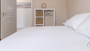 A bedroom with a bed, a wardrobe, and a door leading to another room. - 3-bedroom house, near beach, pets allowed, parking (Gouville-sur-Mer)