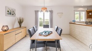 A modern kitchen with a wooden dining table, black chairs, and a pendant light. - 3-bedroom house, near beach, pets allowed, parking (Gouville-sur-Mer)
