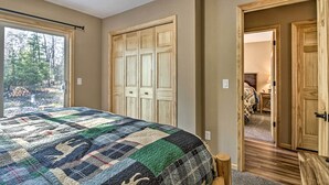Quarto com uma cama grande, um guarda-roupa de madeira e uma porta que dá para outro cômodo.