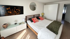 Une chambre à coucher comprenant un lit, une table de chevet, un miroir, une œuvre d’art accrochée au mur et une armoire.