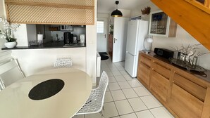 Une cuisine compacte avec un coin repas, un four à micro-ondes, un réfrigérateur et un escalier en bois.