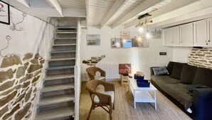 A cozy cabin interior with a stone wall, a staircase, wicker furniture, a white table, and a dark sofa. - Ty Laouen, Peaceful fisherman's cottage, close to the beach, WIFI (Quiberon)