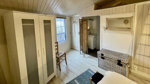 A room with a wooden ceiling, a large window, a wardrobe, a chair, a small table, and a wicker basket. - Ty Laouen, Peaceful fisherman's cottage, close to the beach, WIFI (Quiberon)