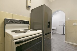 Una cocina con estufa blanca, refrigerador de acero inoxidable y lavadora blanca.