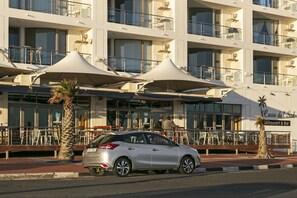 A multi-story hotel with outdoor seating and palm trees.