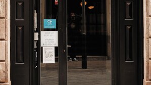En sort dør med dobbelte fløje og et glaspanel, et skilt der angiver '1. sal' og et telefonnummer, samt et lille blåt skilt med 'coq' på.