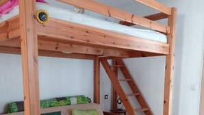 A bunk bed with a ladder, a sofa with cushions, and a small table. - 1 Bedroom Apartment in Carnoux-en-Provence (Carnoux-en-Provence)