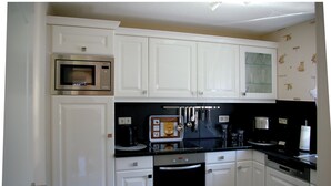 A kitchen with white cabinets, a microwave, a coffee machine, and a black countertop. - Vacation home for max. 6 persons in Duhnen (Cuxhaven)