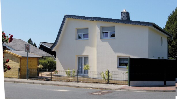 A two-story house with a sloped roof, a chimney, and a small front yard with a fence. - Vacation home for max. 6 persons in Duhnen (Cuxhaven)
